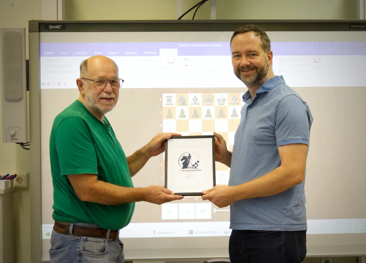 Obmann Reinhard Kammerer und Stephan Seeliger halten das gerahmte neue Logo des Schachklubs Niederabsdorf